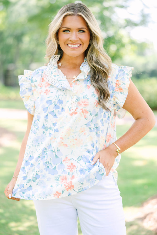 Plus Size white floral top with ruffle cap sleeves, a lace-trimmed collar, and white pants.