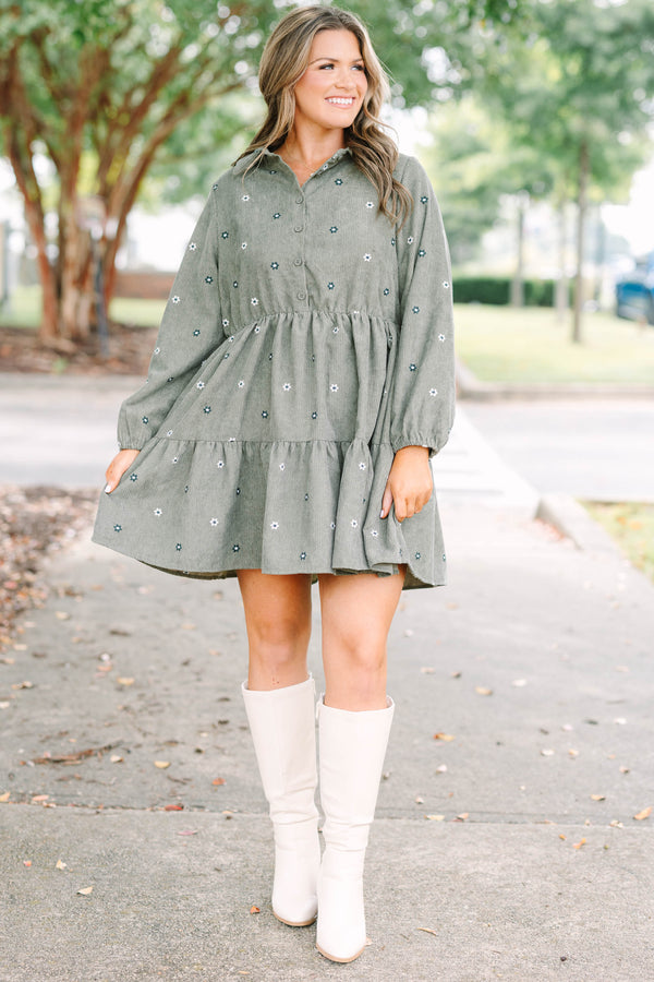 Plus size olive green corduroy babydoll dress with white floral embroidery and button-up front.