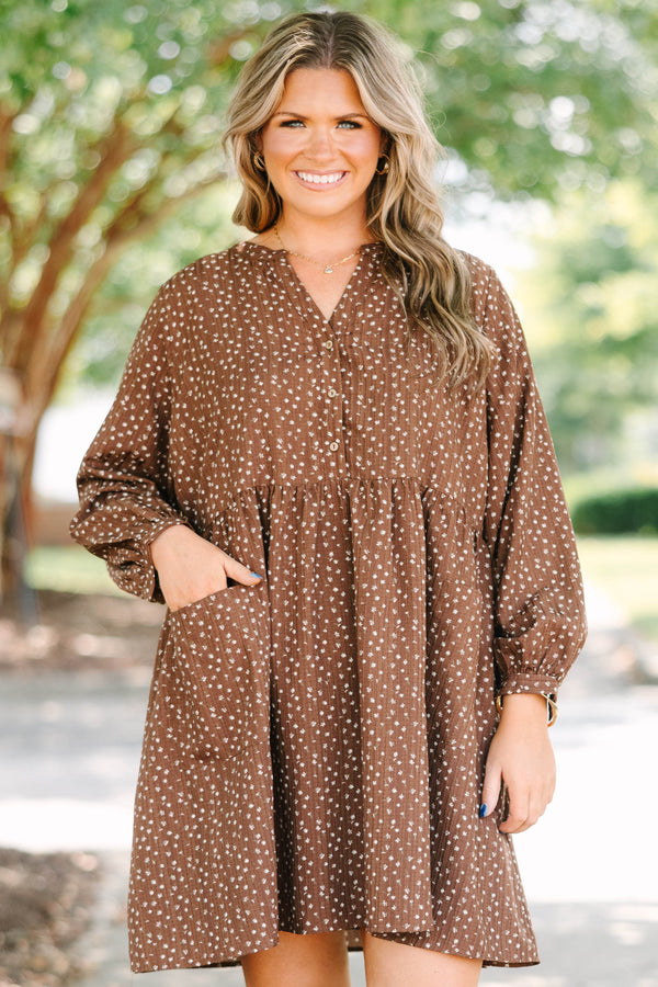 Plus Size brown long-sleeve mini dress with a white floral print, buttoned V-neck, and pockets.