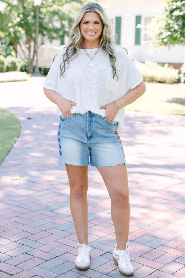Plus Size medium wash high-rise denim shorts with red and blue rhinestone stars and raw hems.