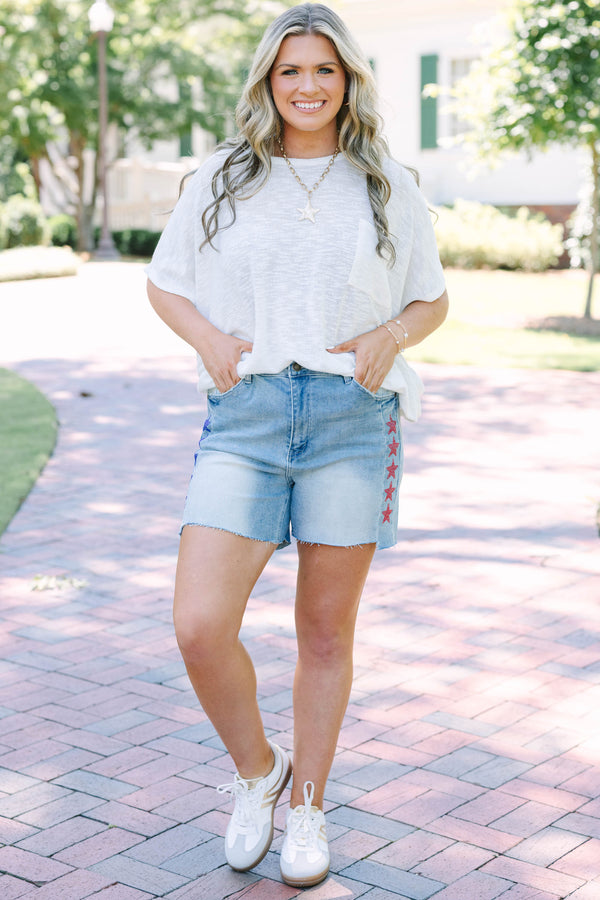 Plus Size medium wash high-rise denim shorts with red and blue rhinestone stars and raw hems.