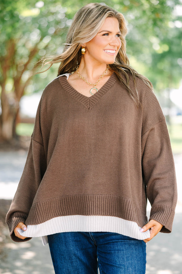 Plus size brown V-neck Sweater with a flowy fit and ribbed hem over blue jeans.