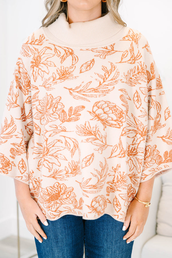Plus size cream turtleneck sweater with orange floral print, flowy fit, and wide sleeves.