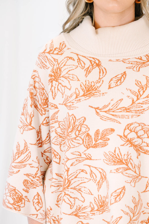 Plus size cream turtleneck sweater with orange floral print, flowy fit, and wide sleeves.