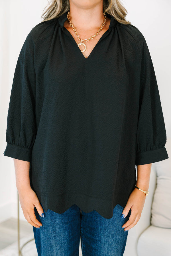 Plus size black top with a flowy fit, V-neckline, and textured polyester fabric.
