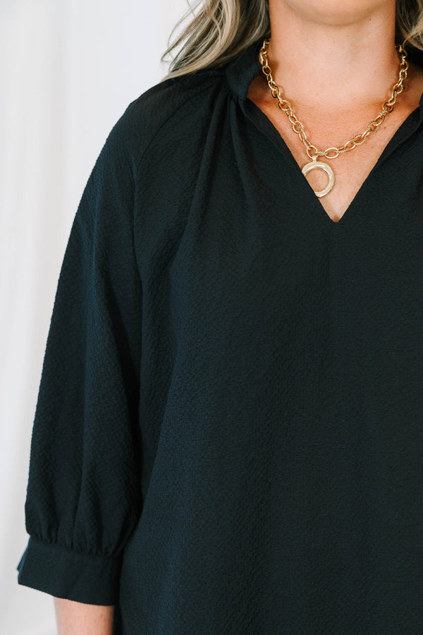 Plus size black top with a flowy fit, V-neckline, and textured polyester fabric.