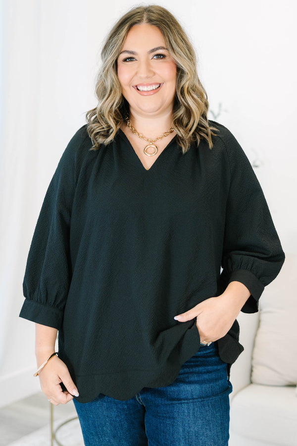 Plus size black top with a flowy fit, V-neckline, and textured polyester fabric.
