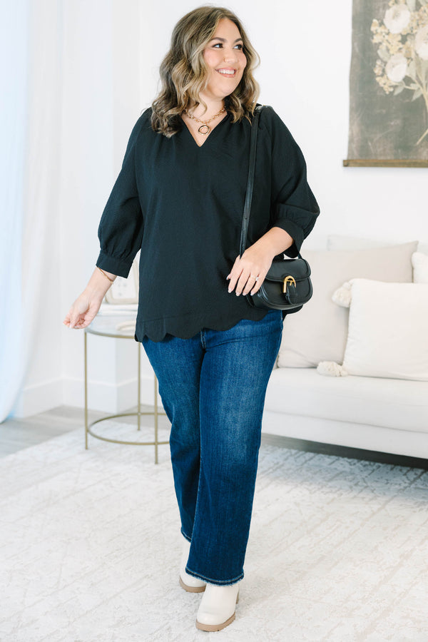 Plus size black top with a flowy fit, V-neckline, and textured polyester fabric.