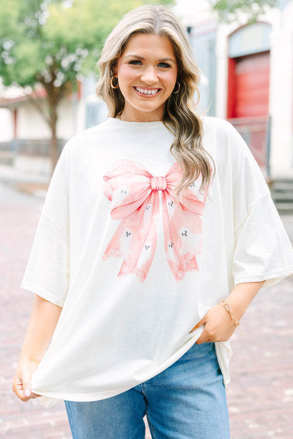 Woman wearing an ivory Girly Ghost Boyfriend Tee with a large pink bow and ghost print.