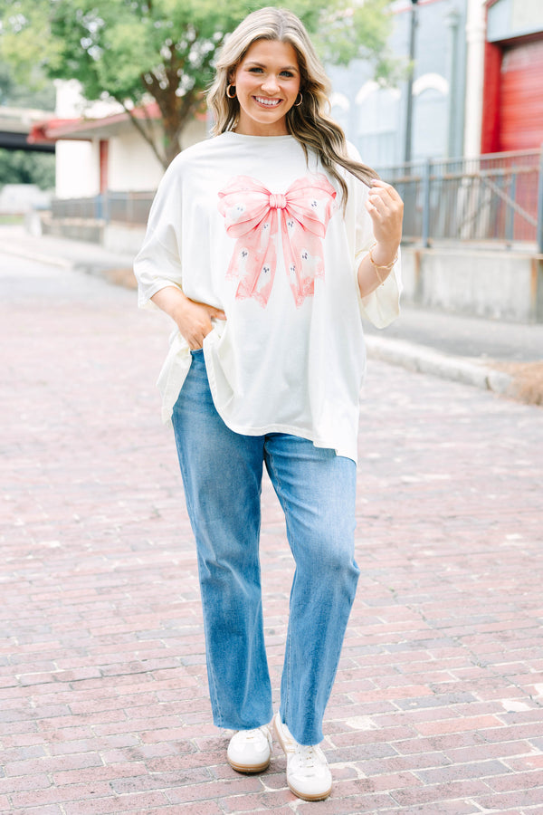 Woman wearing an ivory Girly Ghost Boyfriend Tee with a large pink bow and ghost print.
