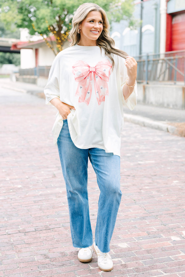 Woman wearing an ivory Girly Ghost Boyfriend Tee with a large pink bow and ghost print.