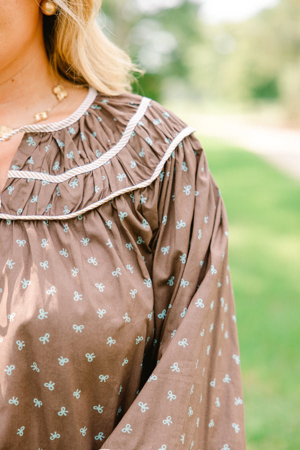 Chic Soul plus size clothing, brown top with long bubble sleeves and a baby blue bow pattern throughout with white stitching details on chest and sleeves 