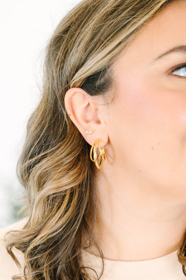 Plus Size gold triple hoop earrings and a small crystal stud on a woman's ear.