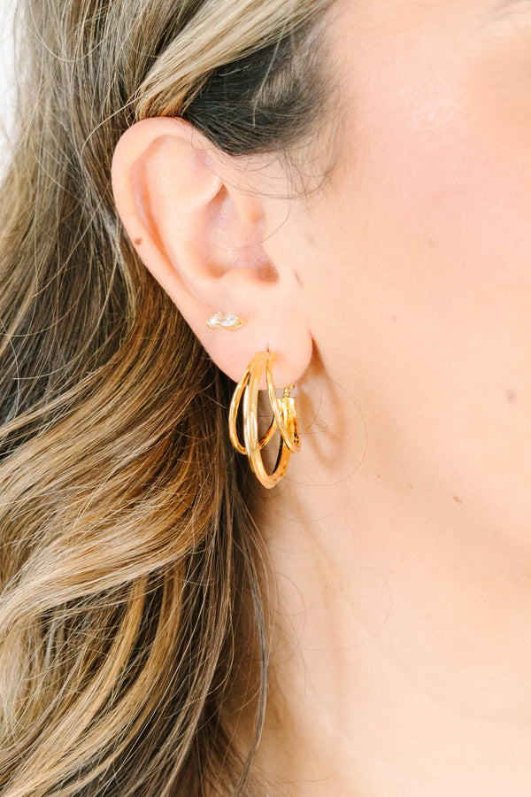 Plus Size gold triple hoop earrings and a small crystal stud on a woman's ear.