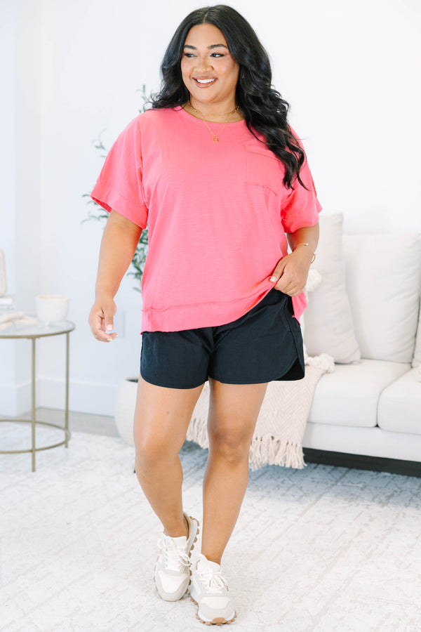 Plus Size pink short sleeve pocket tee with a crew neck and relaxed fit, paired with black shorts.