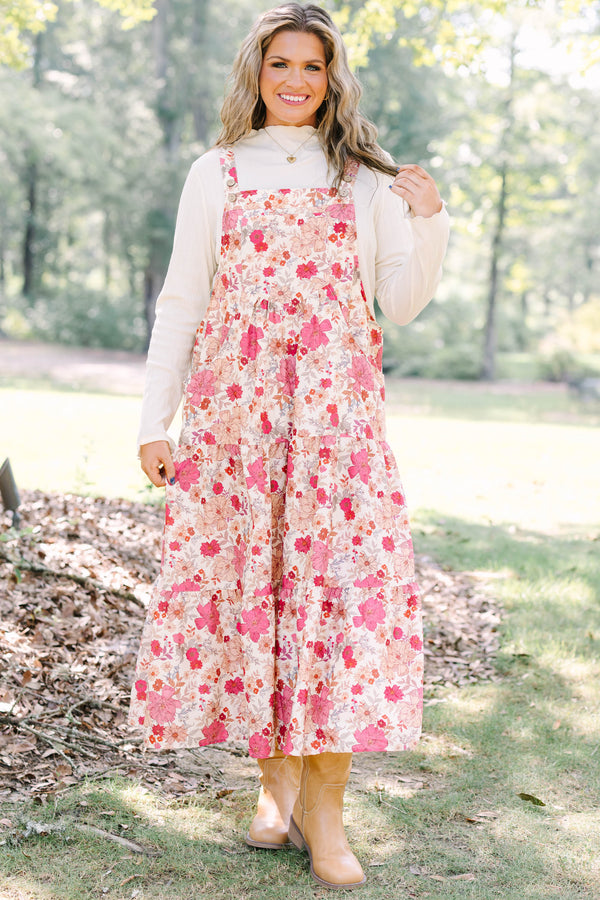 Plus Size pink floral tiered midi dress with overall straps over a white long-sleeve top.