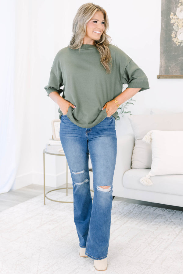 Plus size medium wash flare jeans with distressed knee details and a comfortable high-rise fit.