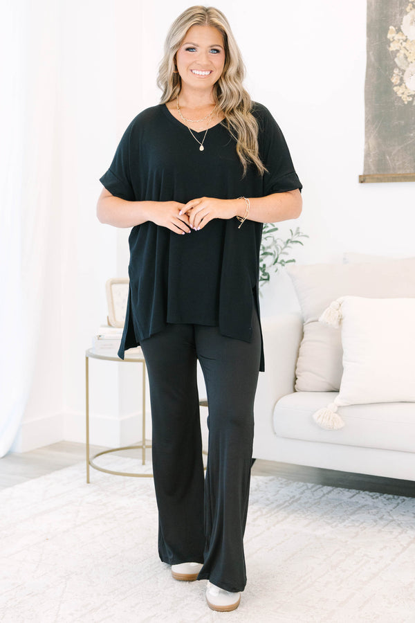 Plus size black flare leggings with a high-waisted, stretchy fit and flowy silhouette.