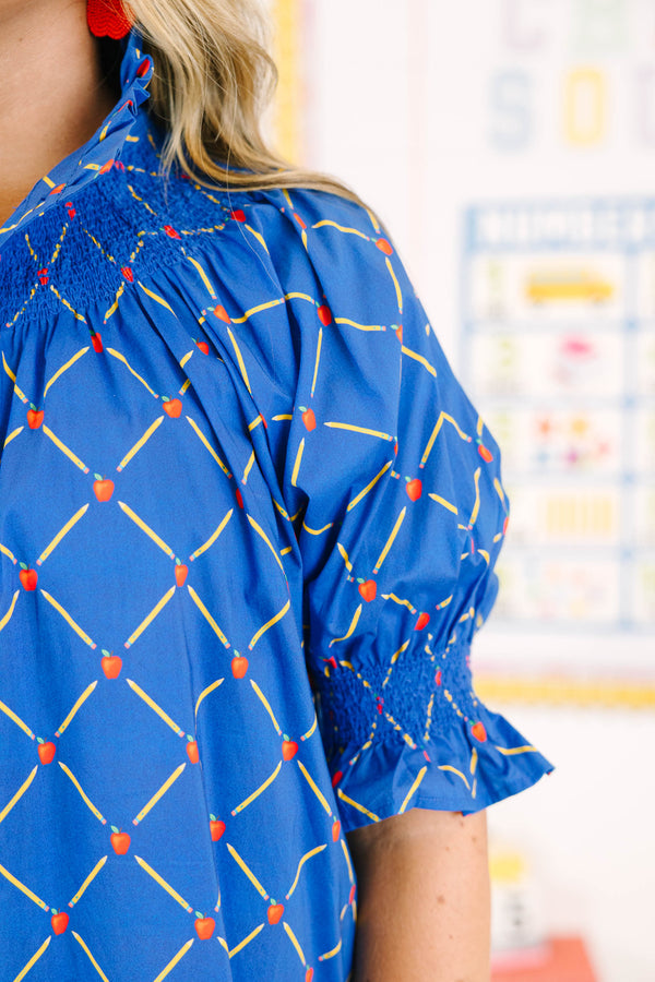 Plus Size navy top with a yellow pencil and red apple grid pattern, smocked neck, and puff sleeves.
