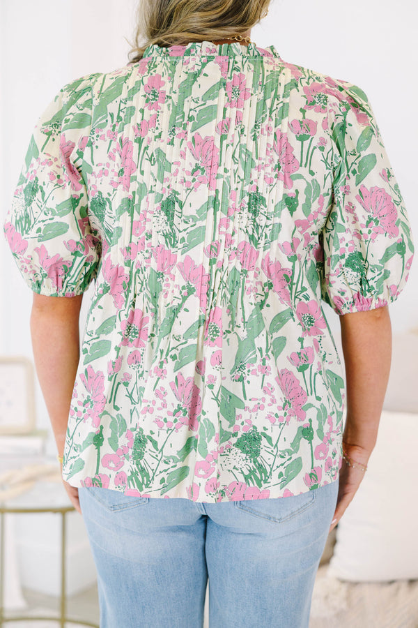 Plus size pink and green floral print top with puff sleeves and a flowy, pleated silhouette.