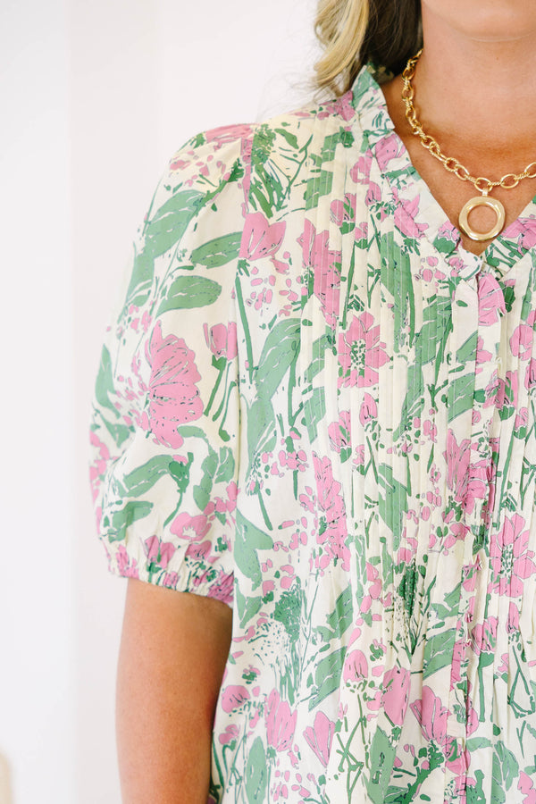 Plus size pink and green floral print top with puff sleeves and a flowy, pleated silhouette.