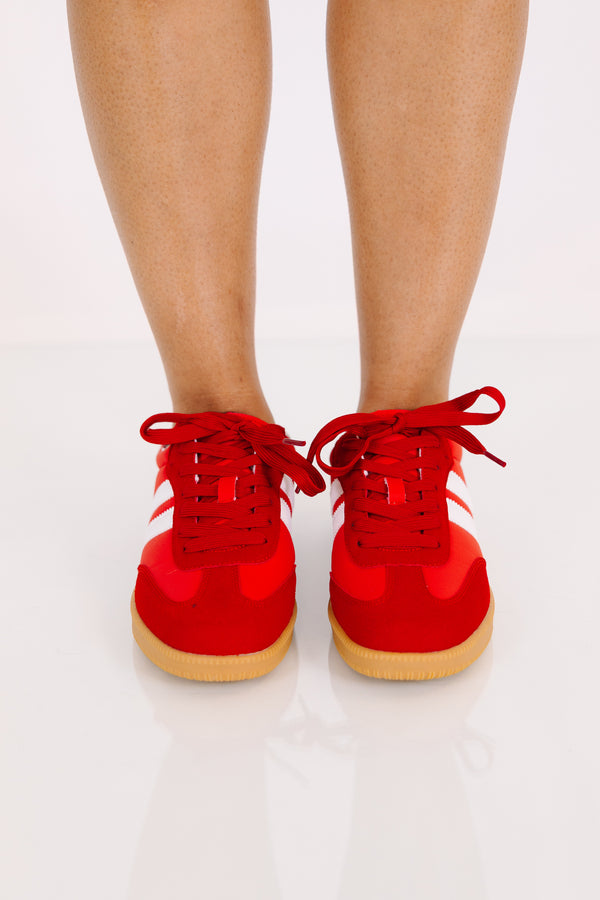 Red low-top sneakers with white side stripes and gum rubber soles.