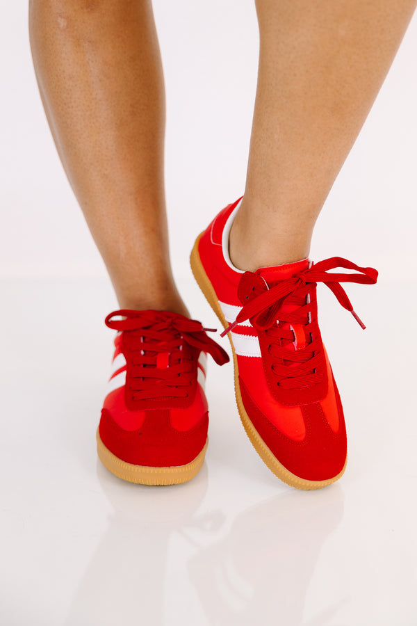 Red low-top sneakers with white side stripes and gum rubber soles.
