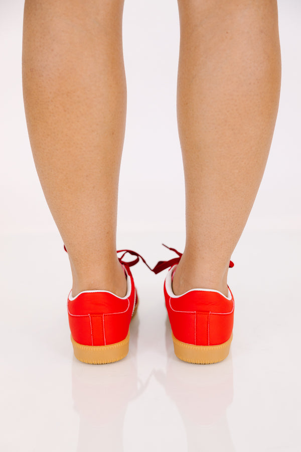 Red low-top sneakers with white side stripes and gum rubber soles.