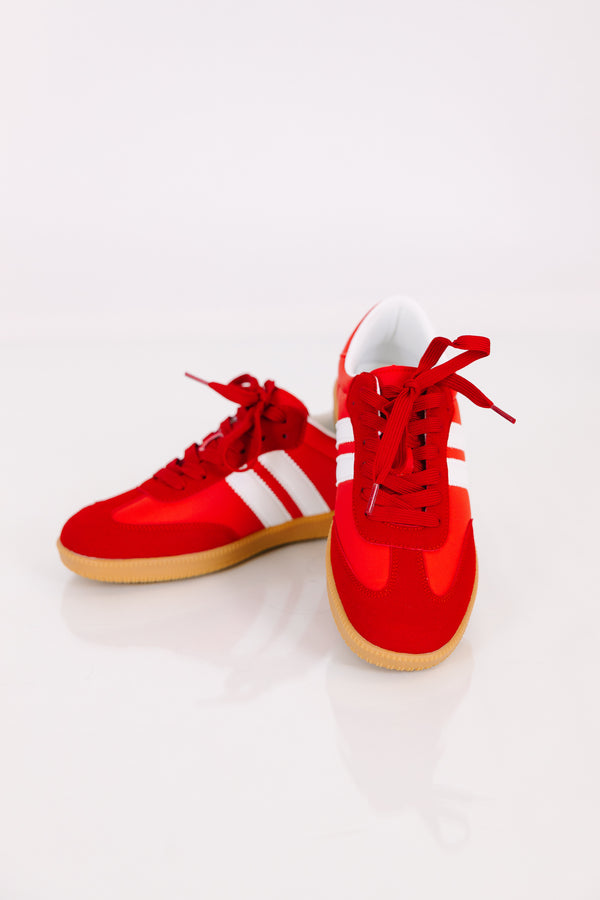 Red low-top sneakers with white side stripes and gum rubber soles.