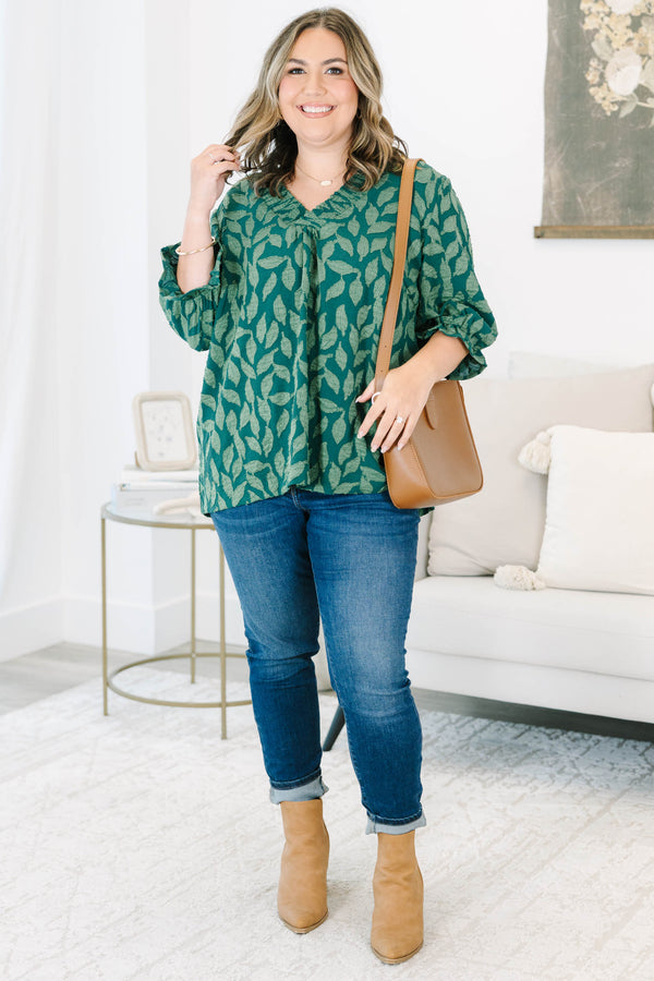 Plus size woman in a green leaf print top with a flowy fit, V-neckline, and ruffled sleeves.
