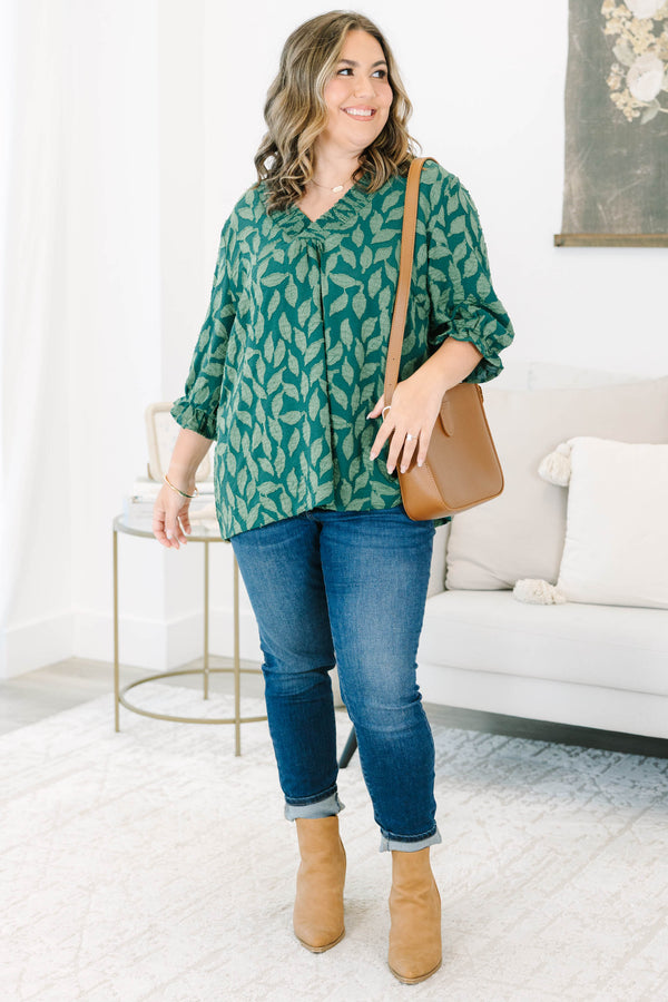 Plus size woman in a green leaf print top with a flowy fit, V-neckline, and ruffled sleeves.