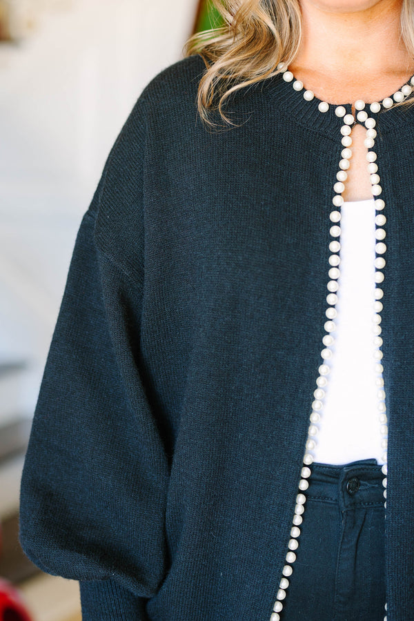 Plus size black cardigan with pearl trim along the neckline and open front, worn over a white top.