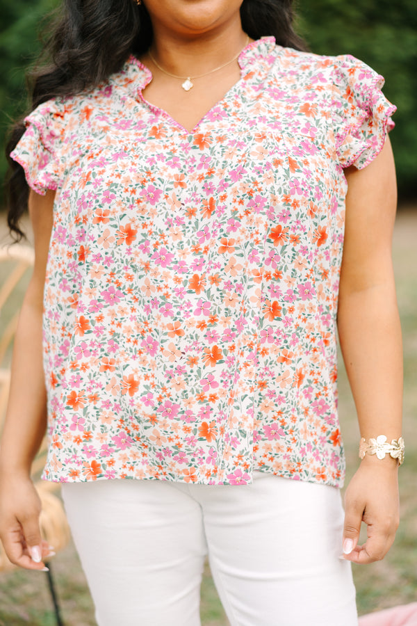 Chic Soul plus size clothing, pink top with a multi-color floral pattern throughout and fluttersleeeves with a slight v-neckline and ruffle details going along the collar of the top 
