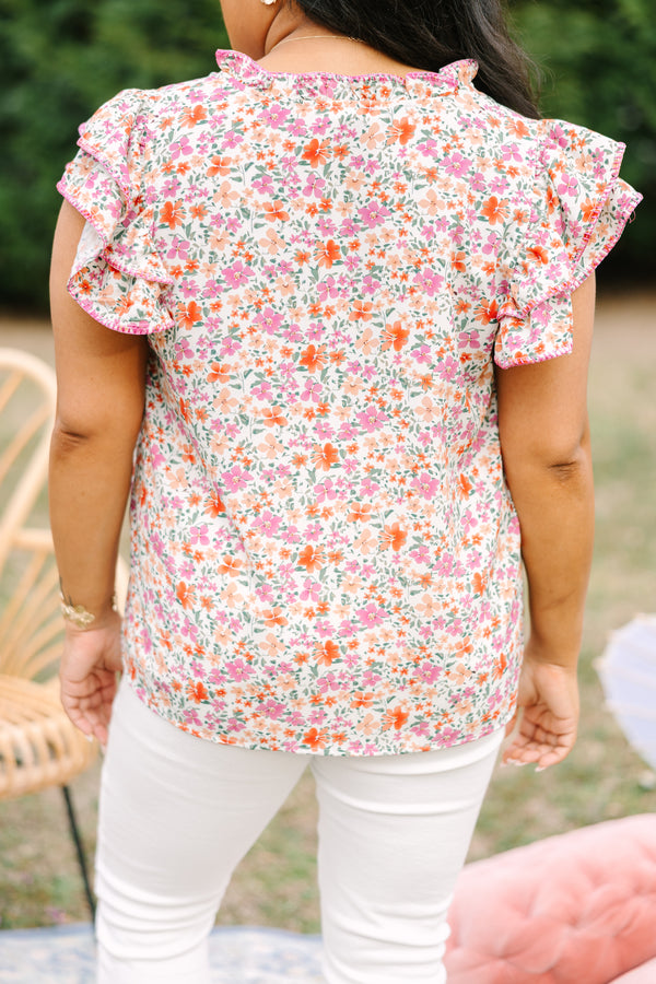Chic Soul plus size clothing, pink top with a multi-color floral pattern throughout and fluttersleeeves with a slight v-neckline and ruffle details going along the collar of the top 
