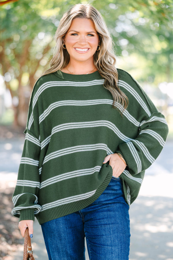 Plus size woman in an olive green oversized striped sweater with a relaxed, flowy fit.