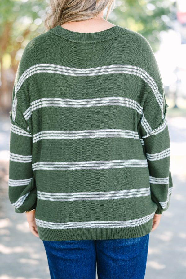 Plus size woman in an olive green oversized striped sweater with a relaxed, flowy fit.