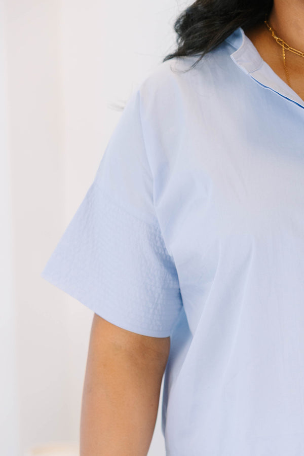 Plus size light blue cotton poplin button-down top with elbow-length sleeves.