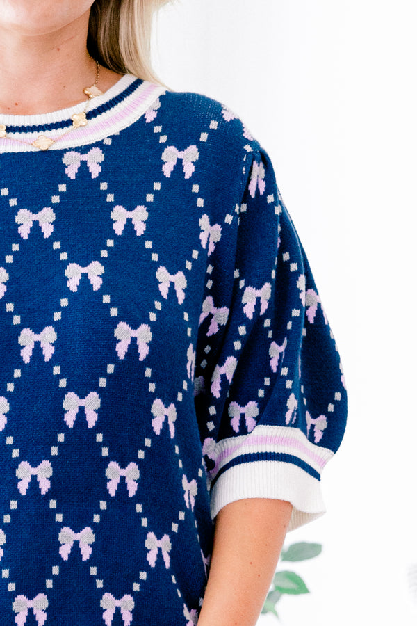 Chic Soul Plus size Clothing, Navy blue short sleeve sweater with a bow print throughout and a white cuff with a stripe on the ends of each sleeve and bottom of the shirt 
