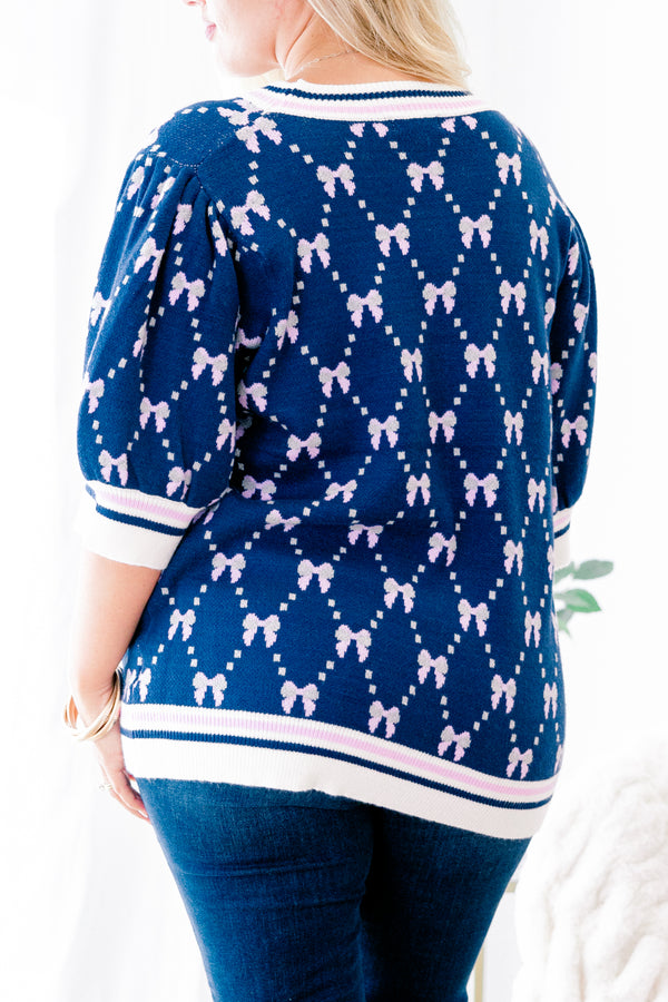 Chic Soul Plus size Clothing, Navy blue short sleeve sweater with a bow print throughout and a white cuff with a stripe on the ends of each sleeve and bottom of the shirt 
