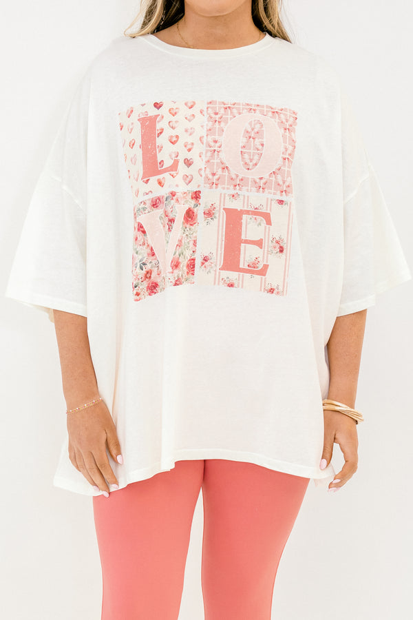 Person wearing a white oversized t-shirt with floral 'LOVE' print and pink pants on a white background