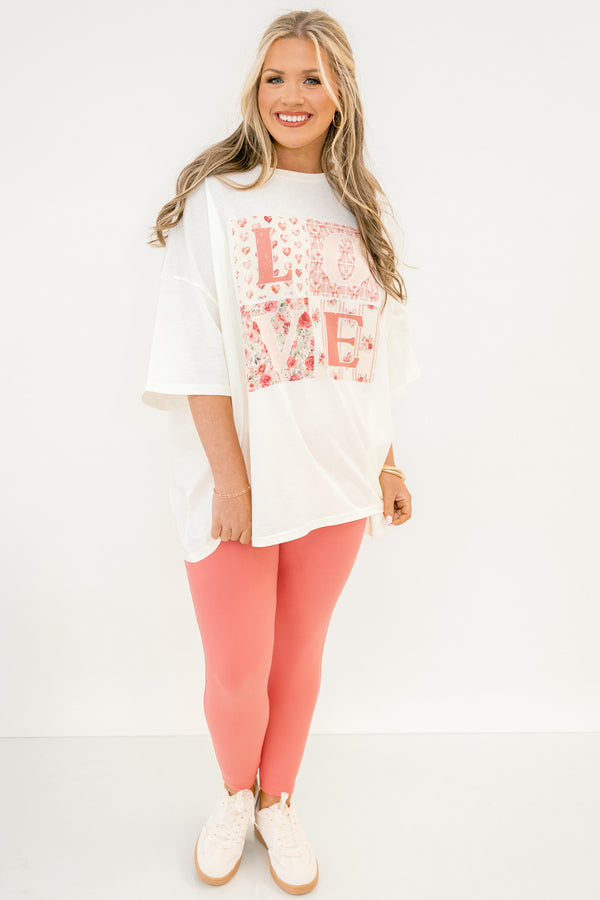 Woman wearing a white oversized shirt with floral text and pink leggings on a white background