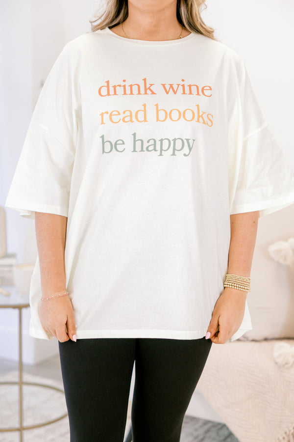 Person wearing a white t-shirt with text 'drink wine, read books, be happy' in a casual setting.