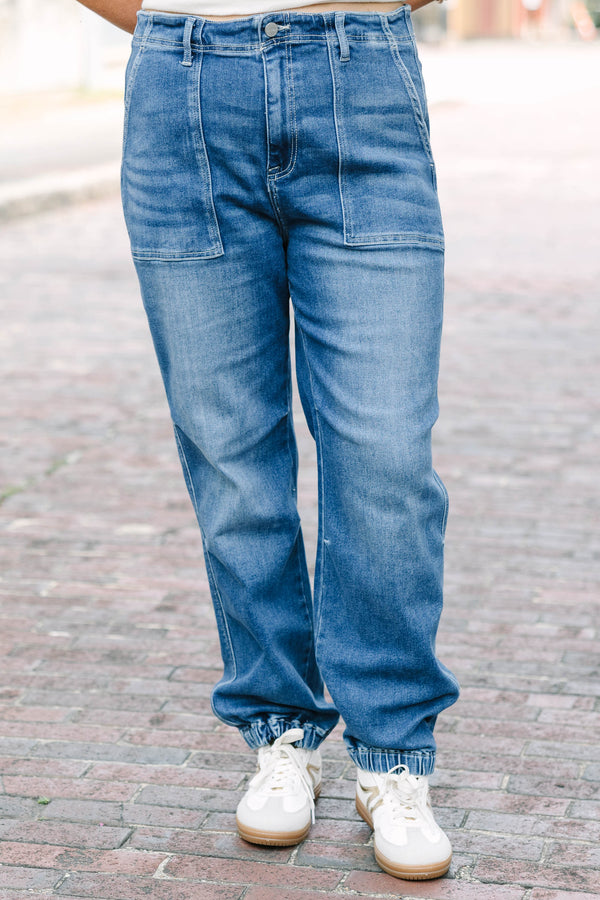Plus Size medium wash high-rise cargo jogger jeans with front patch pockets and elasticized cuffs.