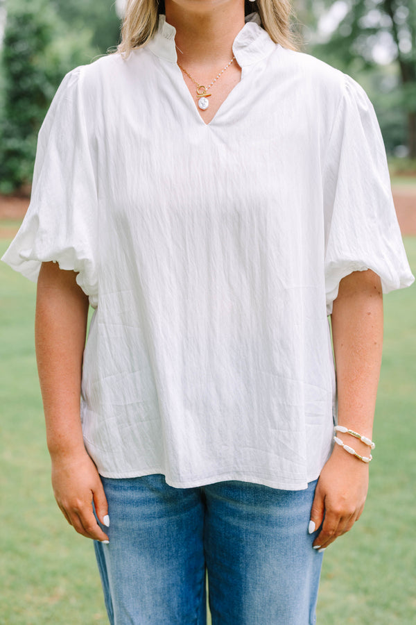 Plus Size ivory top with a ruffled v-neckline and short puff sleeves paired with blue jeans.