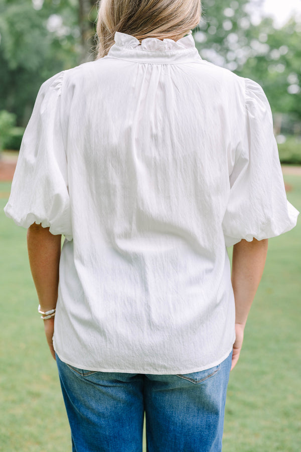Plus Size ivory top with a ruffled v-neckline and short puff sleeves paired with blue jeans.