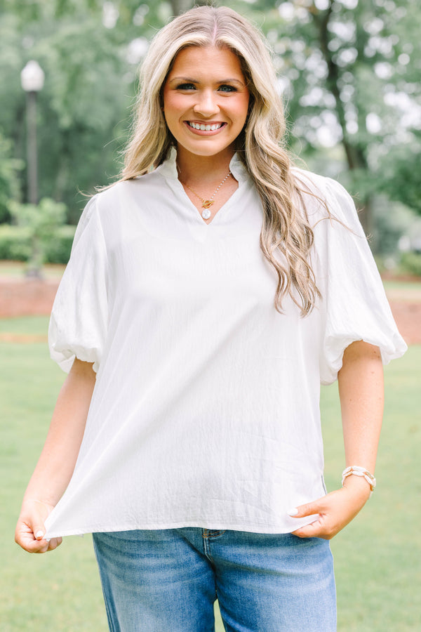 Plus Size ivory top with a ruffled v-neckline and short puff sleeves paired with blue jeans.