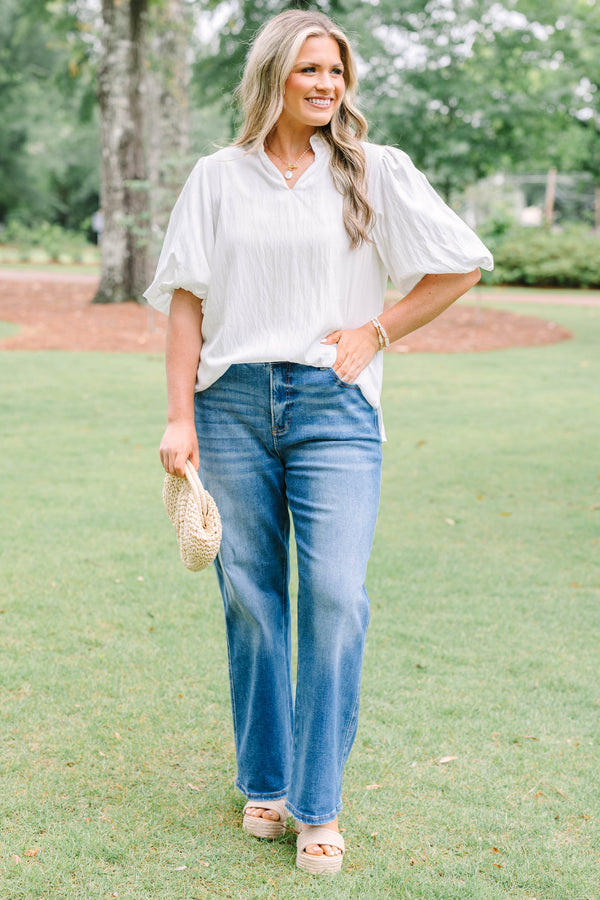 Plus Size ivory top with a ruffled v-neckline and short puff sleeves paired with blue jeans.
