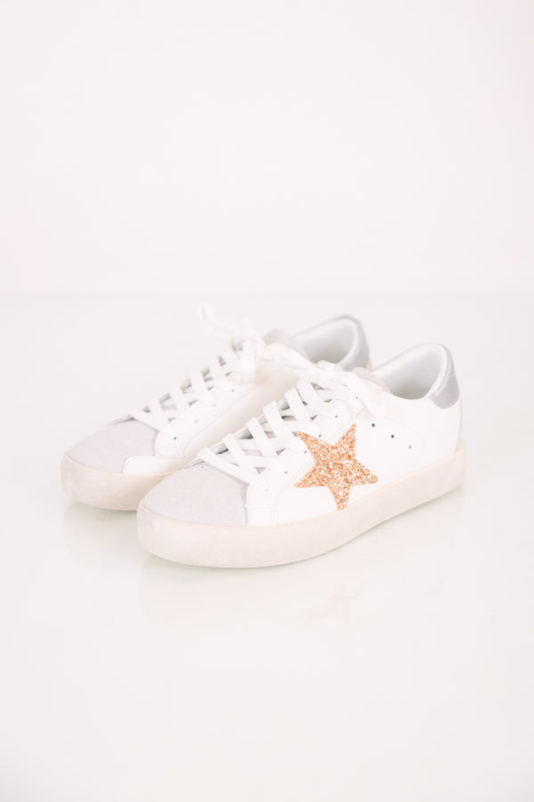 White low-top lace-up sneakers with a silver metallic heel and a gold glitter star accent.