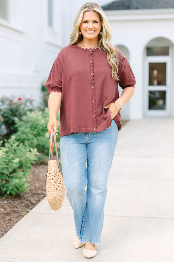 Plus size woman in a brown short sleeve cardigan with scalloped edges and a button-down front.