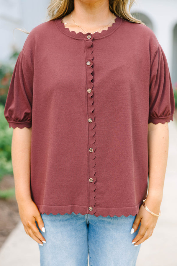 Plus size woman in a brown short sleeve cardigan with scalloped edges and a button-down front.